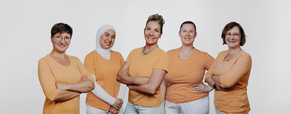 Das Team der Zahnarztpraxis Hansen in orangefarbener Praxiskleidung
